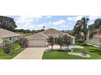 Charming home with a well-maintained lawn, beautiful landscaping, and an attached two-car garage at 2002 Enrique Dr, Lady Lake, FL 32159