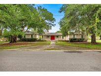 Charming single-story home with mature trees and a vibrant red front door at 4025 Ne 18Th St, Ocala, FL 34470