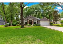 Charming home featuring a manicured lawn, mature trees, and a two-car garage at 4465 Se 48Th Place Rd, Ocala, FL 34480