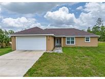Inviting single story home featuring a two-car garage, neutral stucco, and a well-manicured lawn at 5331 Sw 121St Ter, Ocala, FL 34481