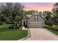 Charming home exterior boasts a two-car garage, stone accents, and a lush green lawn at sunset at 9158 Sw 65Th Loop, Ocala, FL 34481