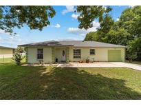 Charming one-story home with a well-manicured lawn, walkway, and light green exterior at 1245 Nw 67Th Pl, Ocala, FL 34475