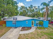 Charming single-story home with a colorful exterior, mature trees, and basketball hoop at 1404 Richmond Rd, Lakeland, FL 33801