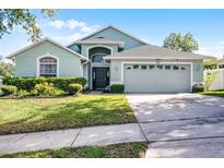 Charming home with a well-manicured lawn, mature landscaping, and an attached two-car garage at 1584 Silhouette Dr, Clermont, FL 34711