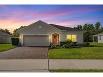 Charming single-story home with a brick driveway, manicured lawn, and a decorative wreath on the front door at 358 Irving Bend Dr, Groveland, FL 34736