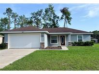 Charming single-story home with manicured lawn and a two-car garage on a sunny day at 5320 Sw 128Th Pl, Ocala, FL 34473