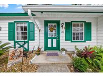 Inviting front door with green trim, a hanging flower basket, and decorative windows add charm to the entrance at 7961 Midway Drive Ter # J102, Ocala, FL 34472