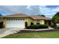 Charming single-story home with a well-manicured lawn, a two-car garage, and yellow paint at 9490 Sw 94Th Ct, Ocala, FL 34481
