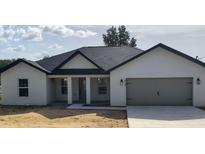 Charming single-story home with a well-manicured lawn and a gray two-car garage at 9721 Bahia Rd, Ocala, FL 34472