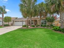 Inviting home featuring lush landscaping, mature palm trees, and a well-manicured lawn at 1266 James Island St, The Villages, FL 32162