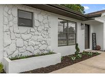 The exterior features a stone accent wall and a well-maintained lawn with decorative plants and flower beds at 21191 Sw Plantation St, Dunnellon, FL 34431
