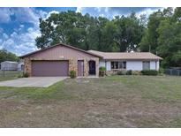 Charming single-story home featuring a stone facade, attached garage, and well-maintained front lawn at 3427 Se 137Th St, Summerfield, FL 34491