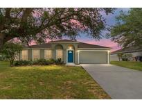Charming single-story home with a well-manicured lawn, inviting blue door, and attached two-car garage at 4531 Se 27Th St, Ocala, FL 34480