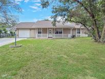 Charming single-story home features a well-manicured lawn and inviting front porch with white railing at 5 Bahia Circle Pl, Ocala, FL 34472