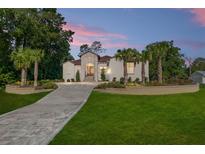 Elegant stucco home featuring a stone facade, paved driveway, and a meticulously landscaped front yard with palm trees at 5034 Nw 75Th Ave, Ocala, FL 34482