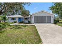 Charming single-story home featuring a screened garage and blue shutters, complemented by lush landscaping at 6495 Sw 109Th St, Ocala, FL 34476