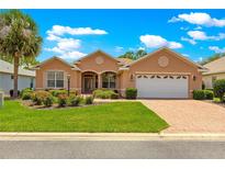 Charming single-story home featuring a well-manicured lawn, brick driveway, and two-car garage at 8380 Sw 82Nd Cir, Ocala, FL 34481