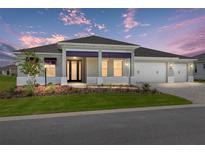 Charming single-story home featuring a three-car garage, manicured lawn, and elegant front porch under a colorful sky at 10026 Sw 85Th Place Rd, Ocala, FL 34481