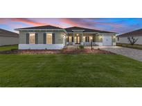 Beautiful single-story home with a manicured lawn, a two-car garage, and colorful twilight skies at 10561 Sw 98Th Pl, Ocala, FL 34481