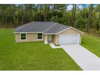 Beautiful tan home features a well-maintained lawn, attached two car garage, and a neutral color scheme at 1083 Sw Winding Hills Rd, Dunnellon, FL 34431