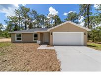 Charming single-story home with a two-car garage, a well-manicured lawn, and a welcoming facade at 1083 Sw Winding Hills Rd, Dunnellon, FL 34431