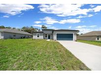 Charming single-story home with a well-manicured lawn, driveway, and attached garage against a blue sky with clouds at 13780 Sw 42Nd Court Rd, Ocala, FL 34473
