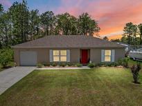 Charming single-story home featuring a well-manicured lawn and a classic red front door at 15138 Sw 50Th Avenue Rd, Ocala, FL 34473