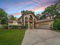 Charming two-story home showcasing a balcony, arched entryway, and lush landscaping at 1630 Se 29Th Ter, Ocala, FL 34471