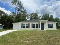 Charming single-story home featuring a well-manicured lawn, attached garage, and classic exterior at 185 Malauka Loop, Ocklawaha, FL 32179