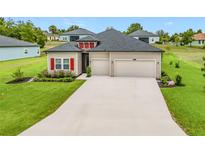 Charming single-story home with a well-manicured lawn, red shutters, and a two-car garage at 19424 Sw 77Th Loop, Dunnellon, FL 34432