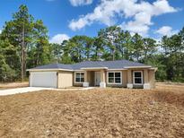 Charming single-story home with neutral stucco siding, an attached two-car garage and manicured lawn at 23213 Nw Mallard Ave, Dunnellon, FL 34431