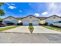 Exterior view of townhomes with individual garages, concrete driveways and well-maintained landscaping on a bright, sunny day at 329 Marion Oaks Blvd # A3, Ocala, FL 34473