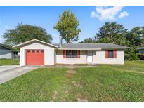 Charming single-story home with a well-maintained lawn, red garage door, and red window shutters at 3428 Ne 17Th Ter, Ocala, FL 34479