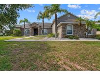 Charming single-story home featuring stone accents, a well-manicured lawn, and tropical palm trees at 4731 Se 34Th St, Ocala, FL 34480