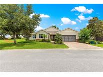 Inviting single-story home featuring manicured landscaping and a brick driveway leading to a two-car garage at 9925 Sw 95Th Loop, Ocala, FL 34481