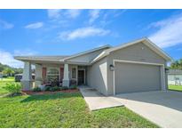 Charming single-story home featuring a two-car garage, landscaped front yard, and covered front porch at 11330 Sw 61St Cir, Ocala, FL 34476