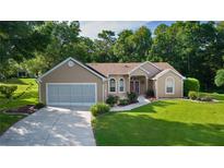 Charming single-story home with a well-maintained lawn, lush landscaping, and an attached two-car garage at 11598 Sw 74Th Ct, Ocala, FL 34476