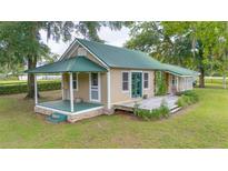 Charming home featuring a metal roof, a covered front porch and a wooden deck surrounded by a spacious green lawn at 1501 Ne 97Th Street Rd, Anthony, FL 32617