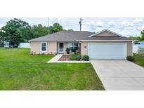 Charming single-story home featuring a well-maintained lawn and attached two-car garage at 1689 Ne 161St Pl, Citra, FL 32113