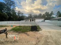 Charming single-story home featuring a white picket fence and attached two-car garage on a landscaped lot at 43 Pine Run, Ocala, FL 34472