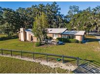 Charming single-story brick home with a metal roof, lush landscaping, and a spacious front yard at 7563 Nw 21St St, Ocala, FL 34482