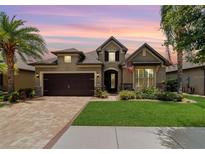 Charming home featuring a well-manicured lawn, brick driveway and two-car garage at dusk at 7814 Sw 97Th Cir, Ocala, FL 34481
