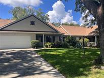 Charming home featuring a lush green lawn, mature trees, and an attached two-car garage at 8450 Sw 90Th St # D, Ocala, FL 34481