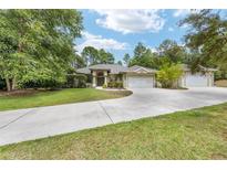 Charming single-story home with a three-car garage and a long driveway, nestled amongst mature landscaping at 8605 Sw 209Th Court Rd, Dunnellon, FL 34431