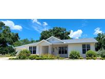 Inviting single-story home with manicured front lawn and beautiful flower beds under a blue sky at 8771 Sw 115Th St, Ocala, FL 34481