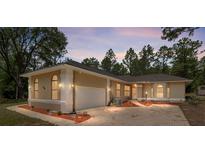 Charming single-story home showcasing stucco siding, an attached two-car garage, arched windows, and a brick driveway at 9180 Sw 202Nd Avenue Rd, Dunnellon, FL 34431