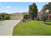 Charming single-story home boasts a well-manicured lawn, mature trees, and a two-car garage with a paved driveway at 611 Allenwood Loop, The Villages, FL 32162