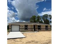 New construction shows a single story home with an attached garage and a modern design at 10401 Se 125Th Ln, Belleview, FL 34420