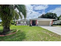 Charming single-story home with a well-maintained lawn and a two car garage with a palm tree in the front yard at 10459 Sw 62Nd Ct, Ocala, FL 34476