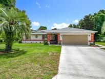 Charming single-story home with a well-manicured lawn, a large garage and a colorful, covered front porch at 10459 Sw 62Nd Ct, Ocala, FL 34476